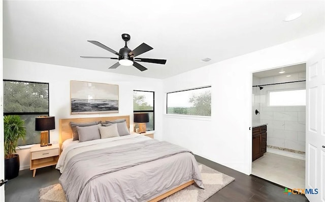 bedroom with connected bathroom, visible vents, dark wood-style floors, and a ceiling fan