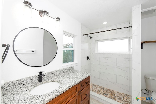 bathroom with vanity, a tile shower, and toilet