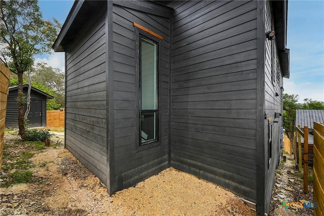 view of side of property with an outbuilding, fence, and a shed