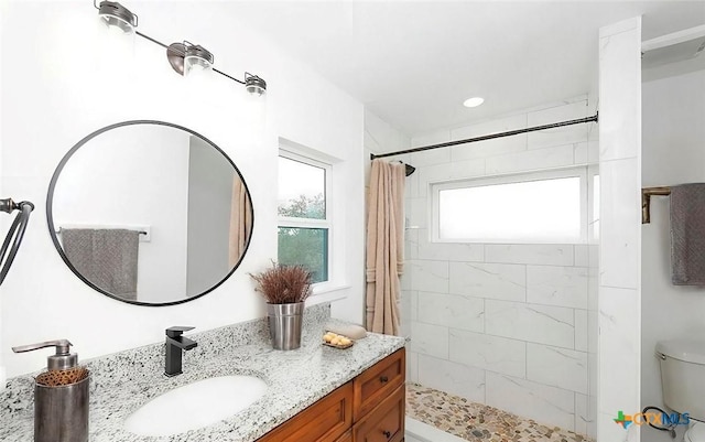 bathroom featuring toilet, vanity, and a tile shower