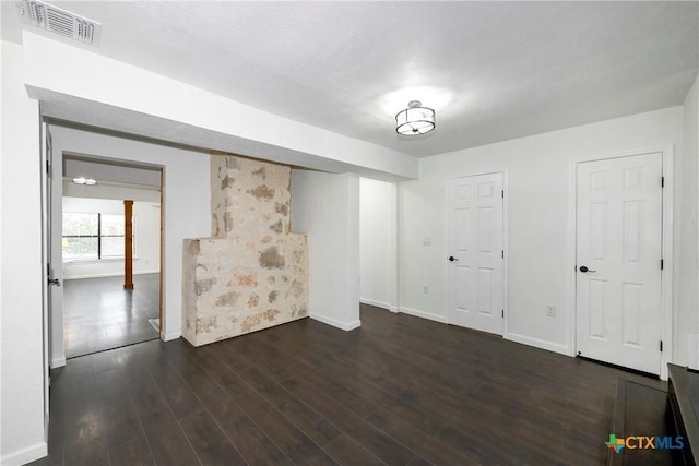 below grade area featuring dark wood finished floors, visible vents, and baseboards