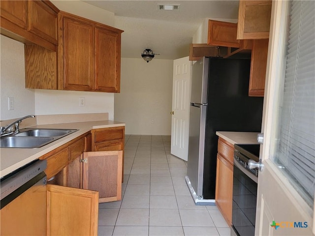 kitchen with light tile patterned floors, stainless steel appliances, a sink, visible vents, and light countertops