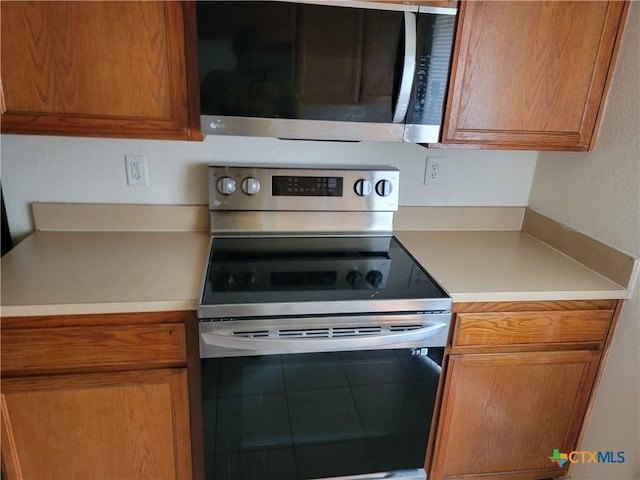 kitchen with stainless steel appliances, brown cabinetry, and light countertops