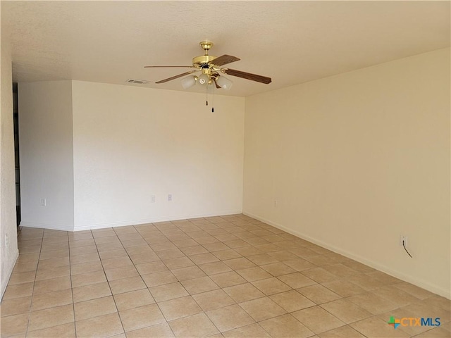 empty room featuring a ceiling fan, visible vents, and baseboards