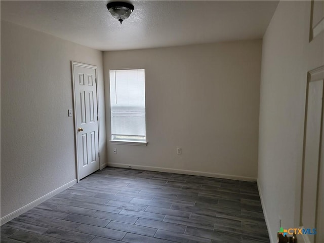 unfurnished room with dark wood-style floors, a textured ceiling, and baseboards