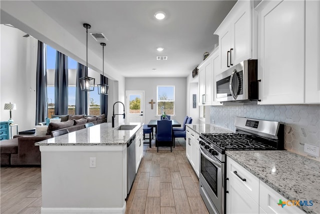 kitchen with white cabinets, stainless steel appliances, sink, and light hardwood / wood-style flooring