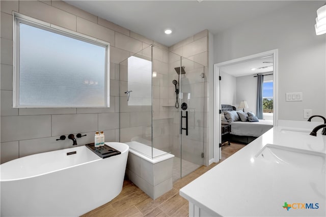 bathroom featuring tile walls, wood-type flooring, vanity, and plus walk in shower