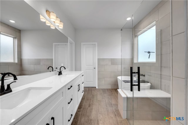 bathroom with tile walls, shower with separate bathtub, vanity, and wood-type flooring