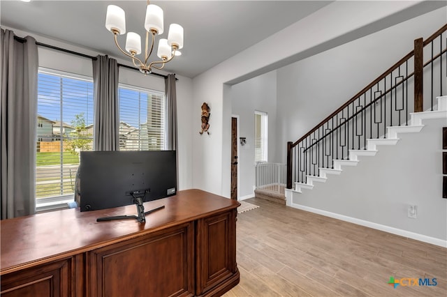 unfurnished office featuring light wood-type flooring and an inviting chandelier