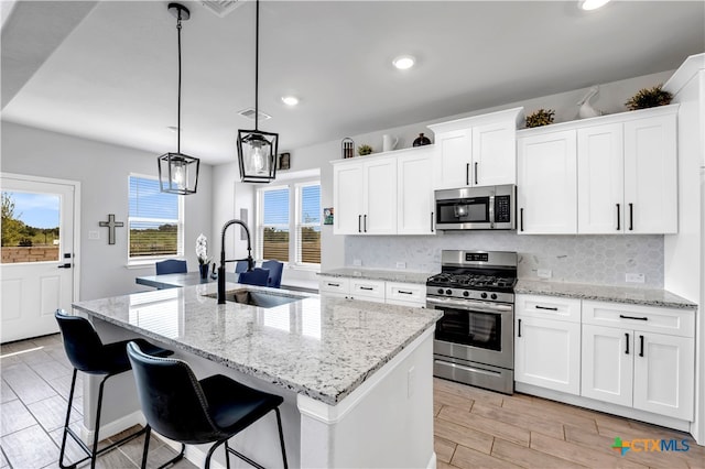 kitchen featuring a center island with sink, sink, white cabinetry, and appliances with stainless steel finishes