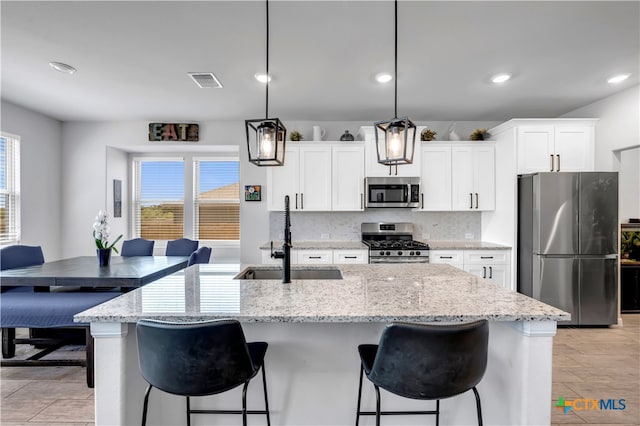 kitchen featuring stainless steel appliances, plenty of natural light, sink, and a kitchen island with sink