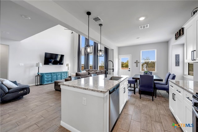 kitchen featuring white cabinetry, hanging light fixtures, and a center island with sink