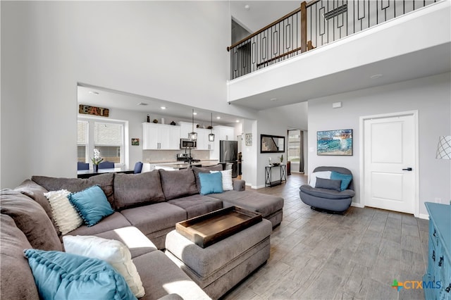 living room featuring a towering ceiling and light wood-type flooring