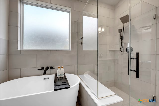 bathroom with shower with separate bathtub and tile walls