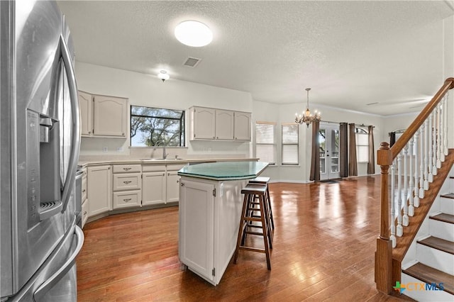 1560 Roadrunner Ln, Canyon Lake, TX 78133 - kitchen featuring stainless steel fridge, a chandelier, a textured ceiling, a kitchen bar, and a kitchen island