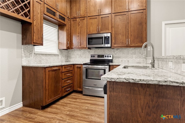 152 Navarro Xing Unit 3B, Seguin, TX 78155 - kitchen with appliances with stainless steel finishes, light stone counters, tasteful backsplash, and light wood-style flooring