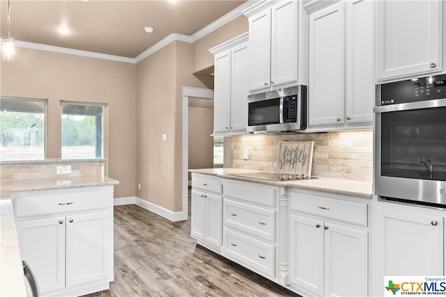 kitchen with crown molding, light stone countertops, light wood-type flooring, appliances with stainless steel finishes, and white cabinetry