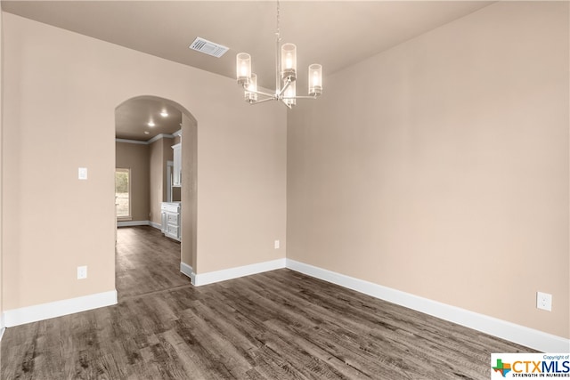 empty room featuring crown molding, dark hardwood / wood-style flooring, and a chandelier