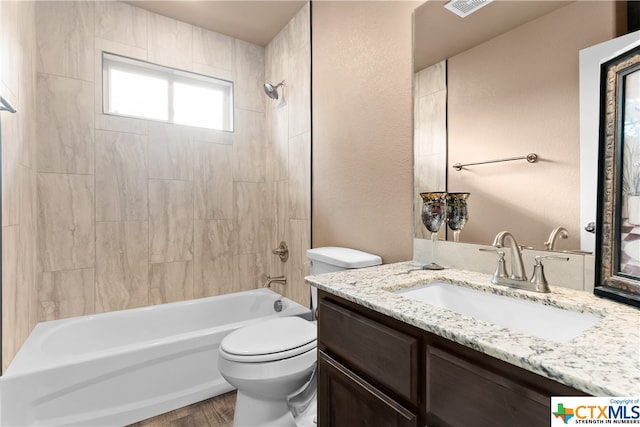 full bathroom featuring hardwood / wood-style floors, vanity, toilet, and tiled shower / bath