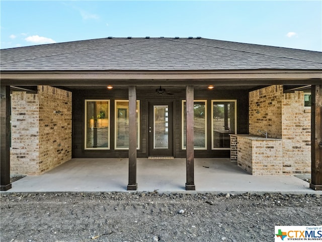 rear view of property featuring ceiling fan and a patio