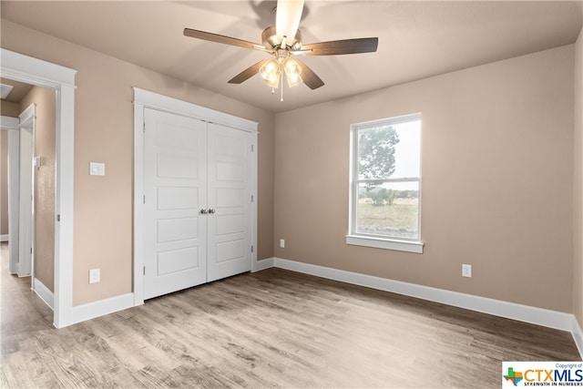 unfurnished bedroom featuring ceiling fan, light wood-type flooring, and a closet