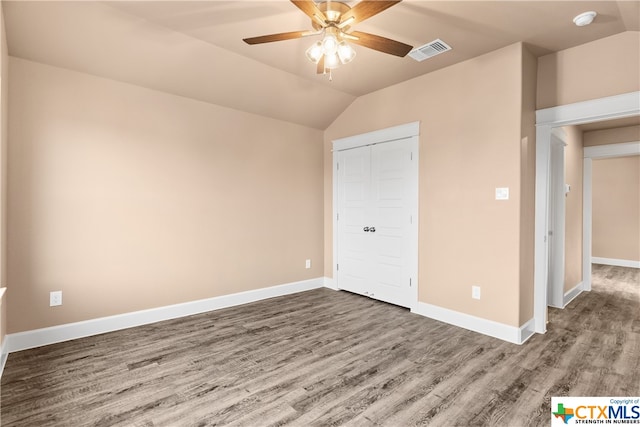 unfurnished bedroom with a closet, ceiling fan, hardwood / wood-style floors, and vaulted ceiling