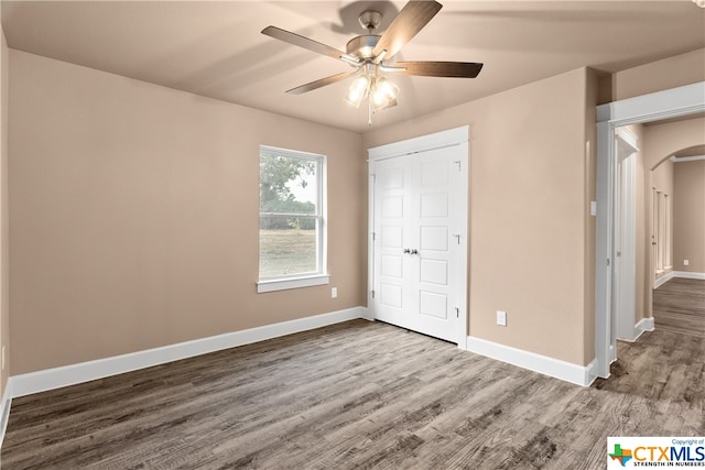 unfurnished bedroom with ceiling fan, a closet, and dark hardwood / wood-style floors