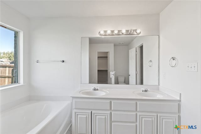 full bath with a sink, double vanity, and a bath