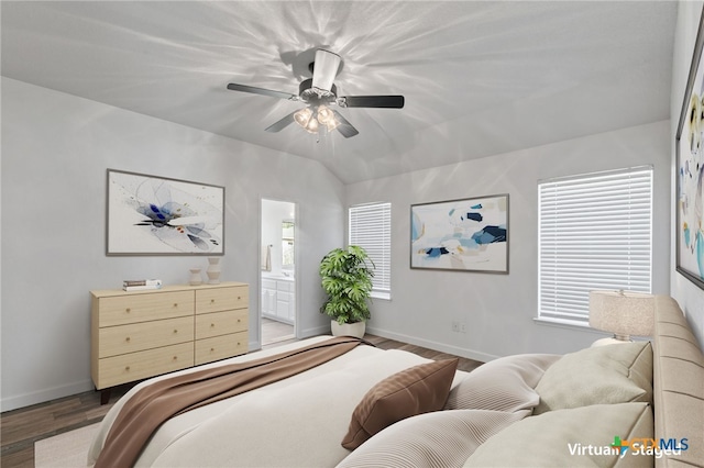 bedroom featuring wood finished floors, baseboards, multiple windows, a ceiling fan, and ensuite bath