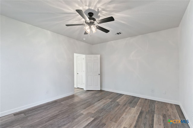 spare room featuring visible vents, a ceiling fan, baseboards, and wood finished floors