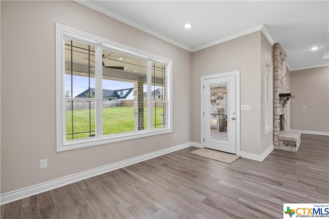 foyer entrance featuring light hardwood / wood-style floors, a stone fireplace, and crown molding