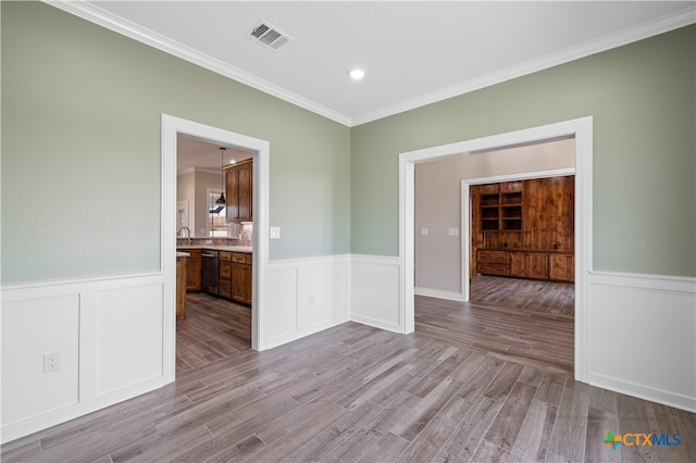 unfurnished room featuring light wood-type flooring, sink, and crown molding