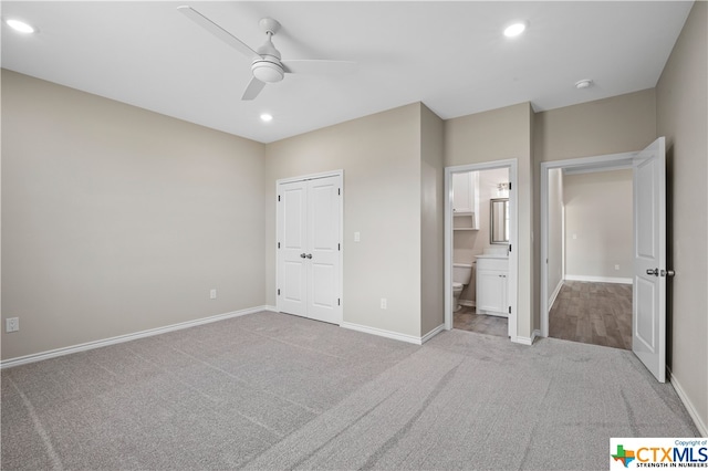 unfurnished bedroom featuring a closet, light carpet, ceiling fan, and ensuite bathroom