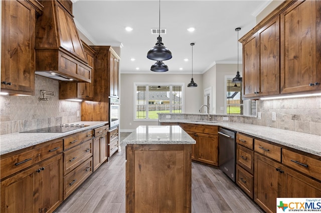 kitchen with light hardwood / wood-style floors, a center island, light stone countertops, pendant lighting, and appliances with stainless steel finishes