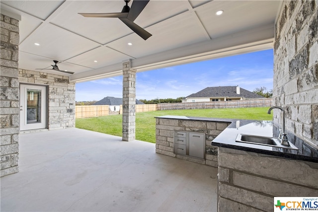 view of patio featuring ceiling fan, area for grilling, and sink