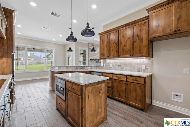 kitchen featuring hanging light fixtures, light stone countertops, light wood-type flooring, and a kitchen island