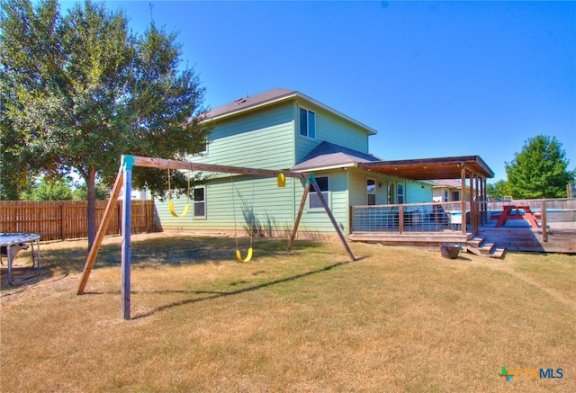 rear view of house featuring a playground, a lawn, and a deck