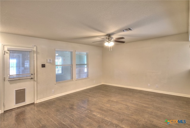 spare room featuring dark wood-type flooring, ceiling fan, a textured ceiling, and a healthy amount of sunlight