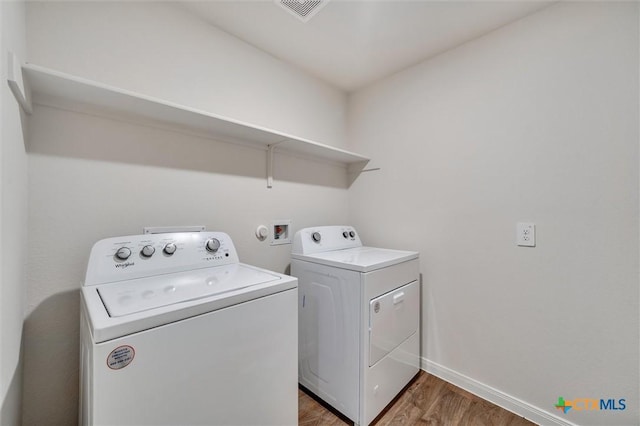 laundry area with wood finished floors, laundry area, washer and dryer, baseboards, and visible vents