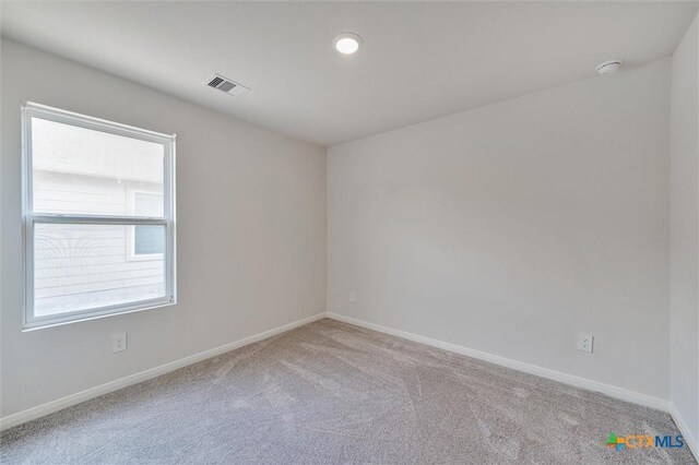 carpeted spare room with visible vents and baseboards