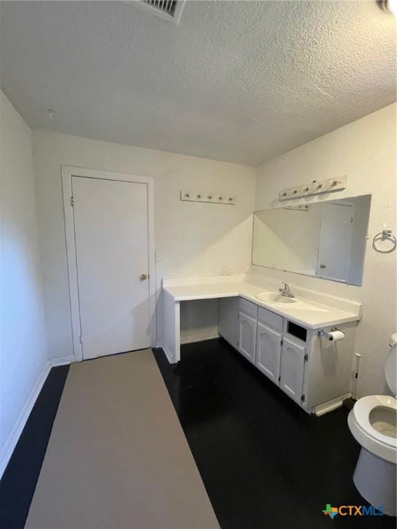 bathroom with vanity, toilet, and a textured ceiling