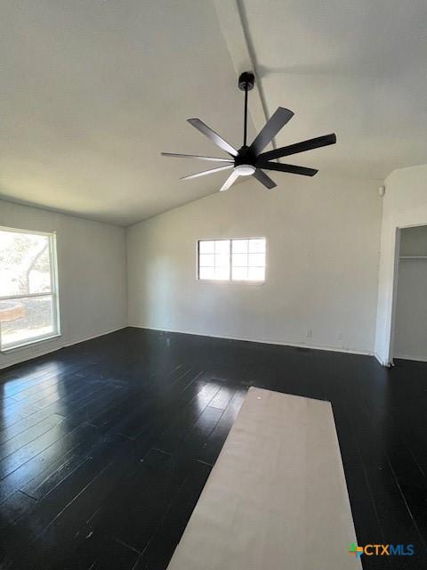 unfurnished room featuring ceiling fan, dark hardwood / wood-style floors, and vaulted ceiling with beams