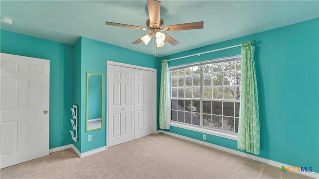 unfurnished bedroom featuring light carpet, a closet, and ceiling fan