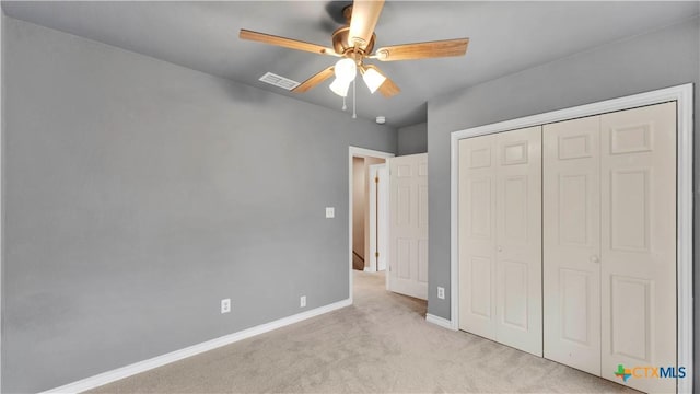 unfurnished bedroom featuring ceiling fan, a closet, and light colored carpet