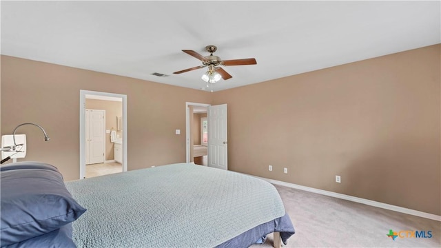 bedroom featuring ceiling fan, ensuite bathroom, and light colored carpet