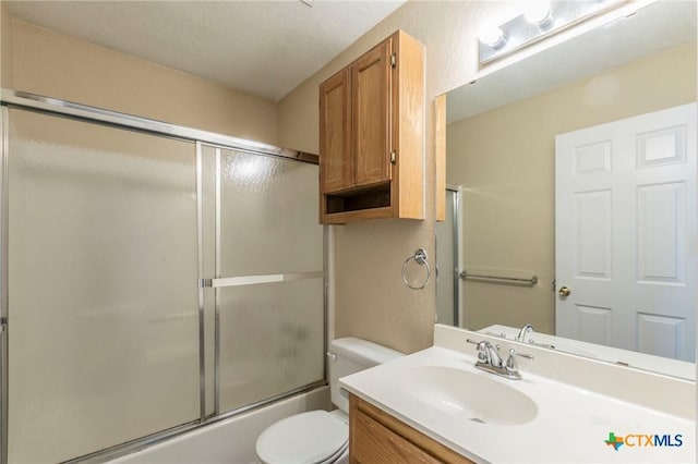 full bathroom featuring vanity, enclosed tub / shower combo, a textured ceiling, and toilet