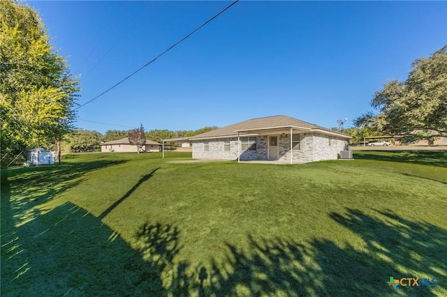 rear view of property featuring a lawn and central air condition unit