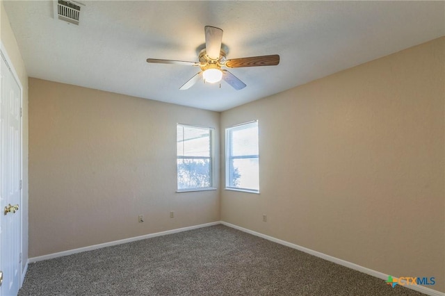 spare room featuring ceiling fan and dark carpet