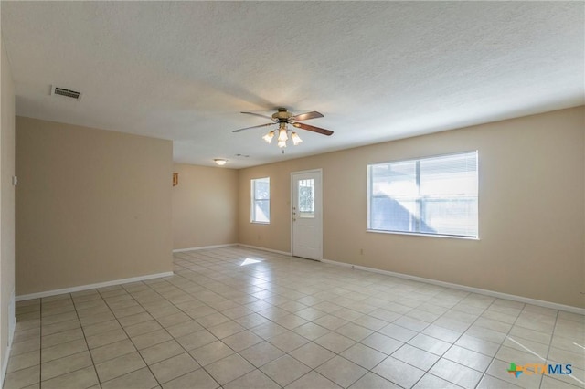 tiled spare room with ceiling fan and a textured ceiling