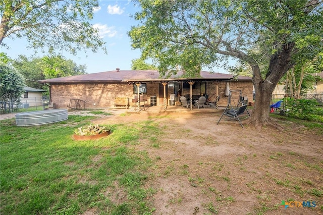 rear view of house featuring brick siding, fence, a yard, a patio, and a jacuzzi
